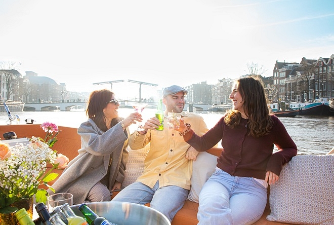 People enjoying drink on open boat lovely cruises view of amstel